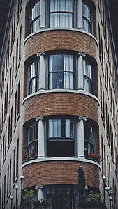 red petaled flowers in balcony of brown bricked building at daytime thumbnail