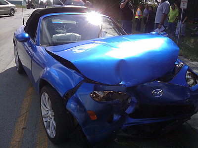 wrecked blue Mazda coupe on highway during daytime thumbnail