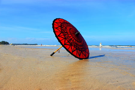 red and black umbrella on seashore thumbnail