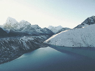 body of water beside mountain filled of snows thumbnail