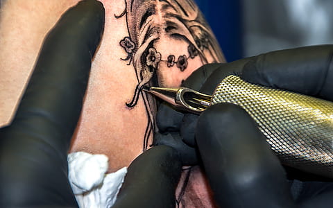 brass-colored tattoo machine on human skin thumbnail