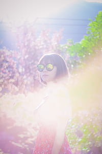 woman standing surrounded by leafed plants thumbnail