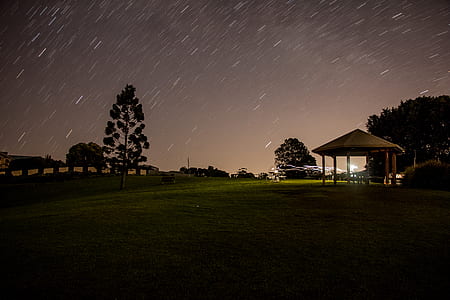 white gazebo surrounded green grass field under night sky thumbnail