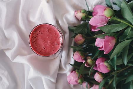 bouquet of pink flowers near glass filled with pink liquid thumbnail