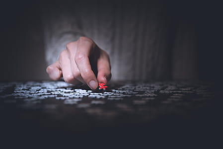 person holding a red jigsaw puzzle piece thumbnail