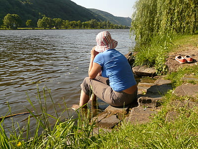 person sitting near river during daytime thumbnail