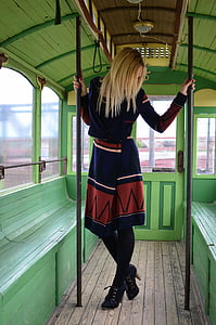 photo of woman in blue-orange-and-white wrap coat dress inside vehicle holding two poles thumbnail