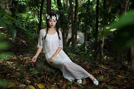 woman sitting on rock surrounded with trees thumbnail