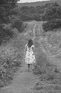 grayscale photography of barefooted woman walking on pathway surrounded by trees thumbnail