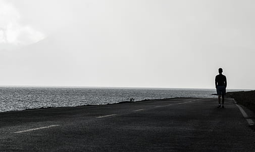 man standing on gray pavement near sea thumbnail