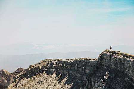 A young caucasian hiker clicking photographs on a rocky edge thumbnail