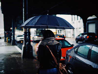 woman holding umbrella while walking on street thumbnail