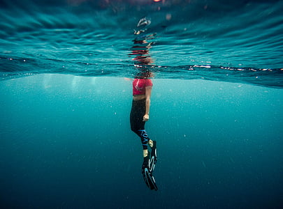 woman wearing red cap-sleeved top submerge into water thumbnail