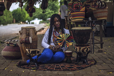 woman sitting holding paper wind mill between drum instruments thumbnail