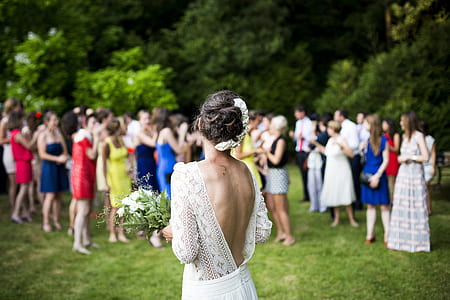 women wearing wedding dress holding bouquet white flower preparing to toss over group of women thumbnail