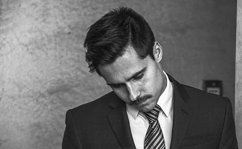 man wearing black top looking downward thumbnail