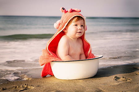 baby sitting on white basin on seashore thumbnail