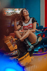 woman in white and black cap-sleeved shirt sitting on motorcycle arcade machine thumbnail