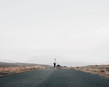 person skating in middle of concrete road thumbnail