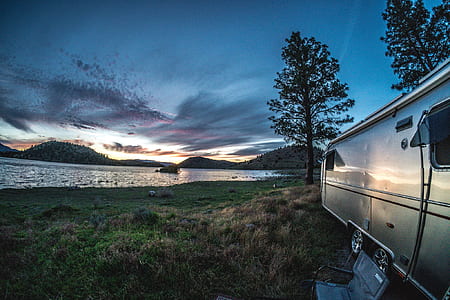 silver travel trailer near body of water thumbnail