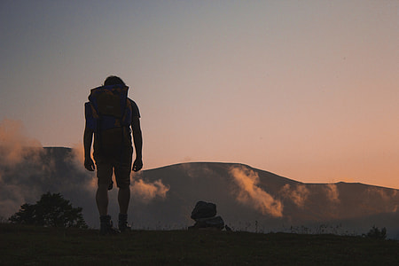 man carrying backpack standing near rocks at golden time thumbnail