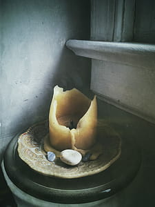 Beige Candle on Beige Saucer Plate Beside Polished Pebbles Near Window thumbnail