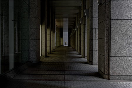 person standing between gray concrete pillars of building architectural photography thumbnail