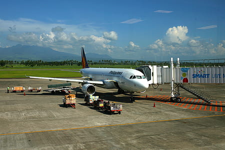 white airplane on field under white clouds thumbnail