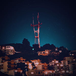 houses near red and white metal tower under starry sky thumbnail