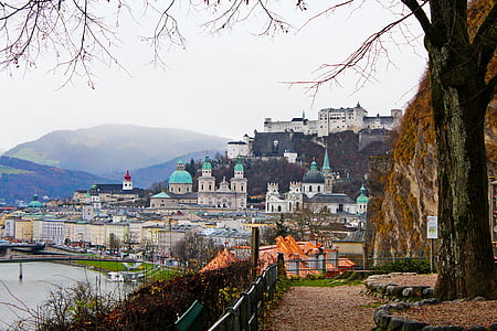 landmark photography of buildings beside large body of water near mountain thumbnail