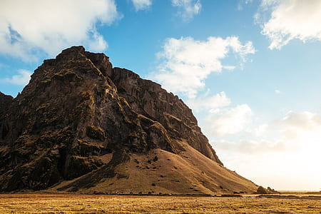 brown stone hill under cloudy sky at daytime thumbnail
