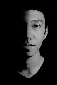 grayscale photo of a man with half of his face in the shadow thumbnail