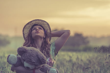 woman carrying bear plush toy on grass field thumbnail