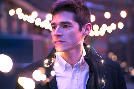 man in white collared shirt with black jacket with string lights thumbnail