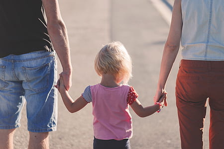 portrait photography of people holding child walking on street during daytime thumbnail