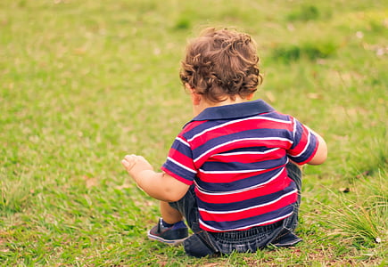 boy sitting on green grass at daytime thumbnail