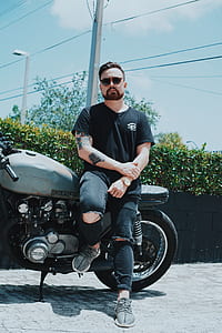 man sitting on gray Suzuki cruiser motorcycle during daytime thumbnail