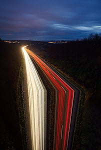 time-lapse photography of highway surrounded by trees under cloudy skies thumbnail