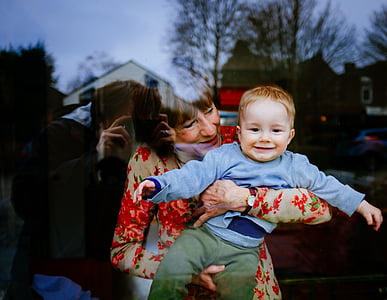 woman carrying baby in gray sweater thumbnail