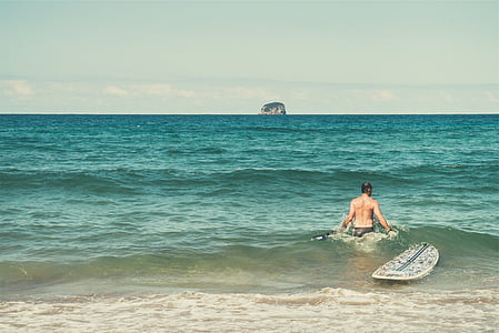 man walking in body of water with surfboard thumbnail