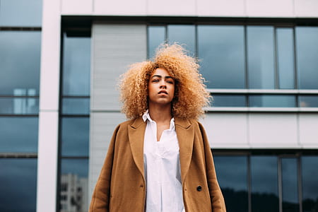 woman wearing brown blazer standing in front of building thumbnail