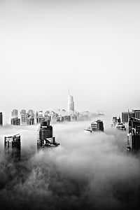 grayscale photo of high rise buildings covered with clouds thumbnail