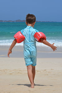 boy in blue wet suit standing on seashore thumbnail