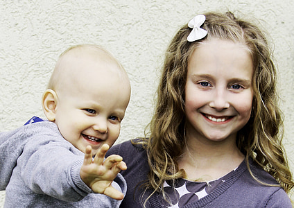 girl holding toddler wearing gray sweater thumbnail